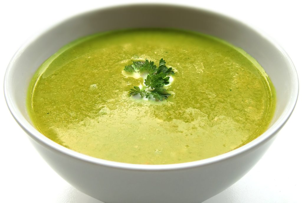 Green pea soup with cilantro on top sitting in a white bowl