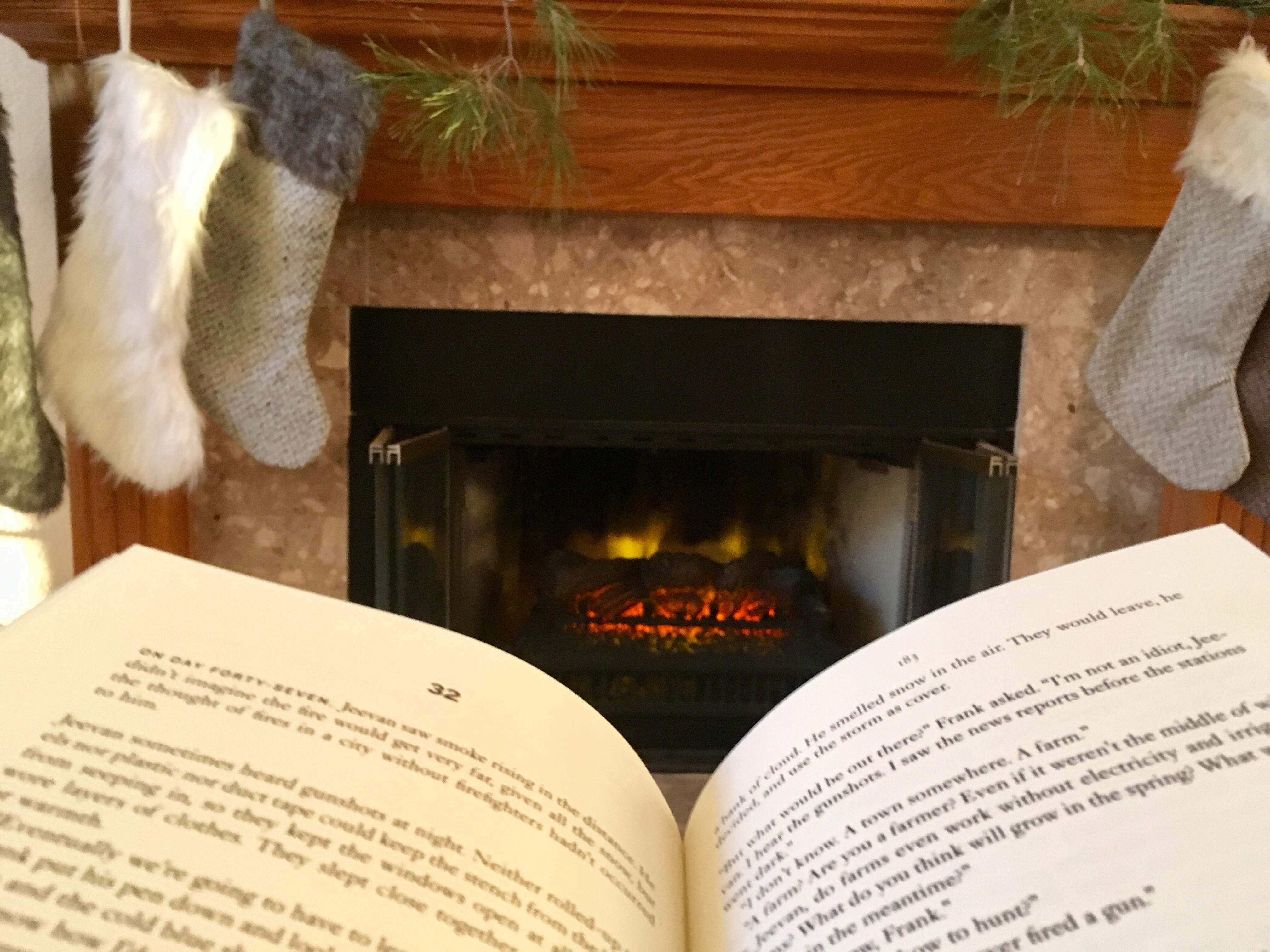 Open book sitting in front of fireplace with Christmas stockings