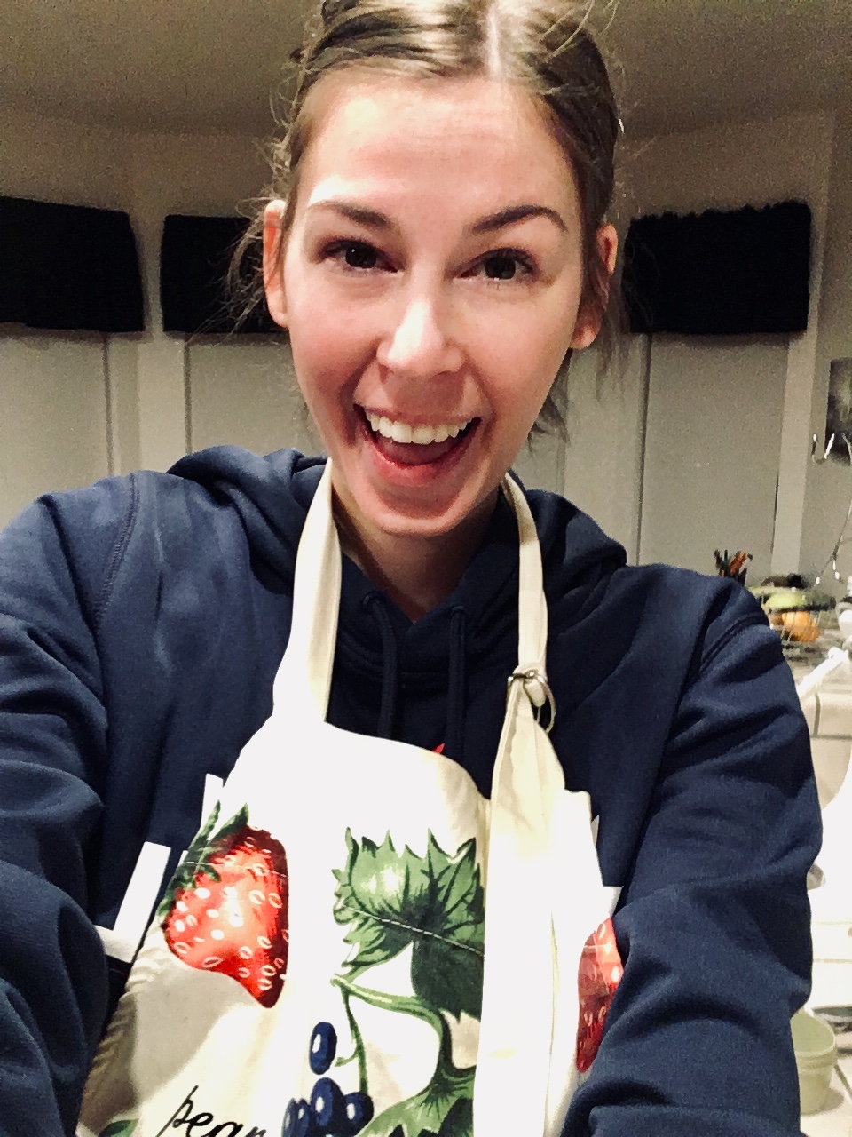 Jenna smiling wide wearing baking apron in kitchen