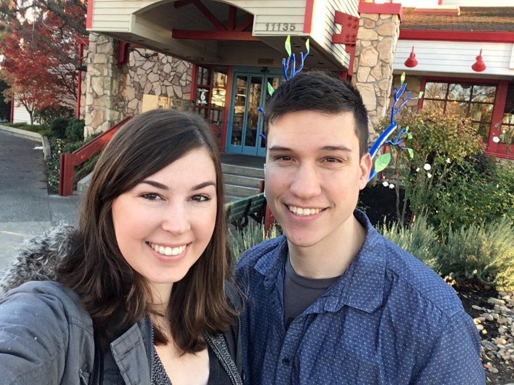 Jenna with huge prednisone cheeks standing beside husband in front of restaurant