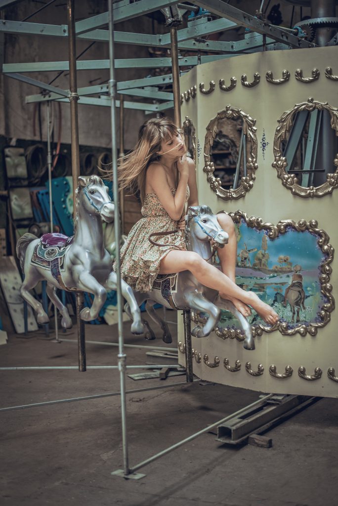 Girl sitting dreamily on horse on carousel
