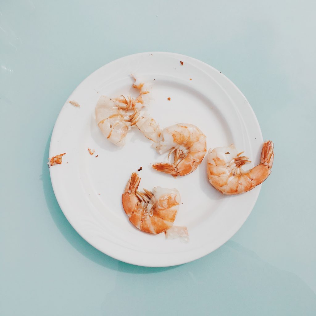 White plate with four large shrimp on it