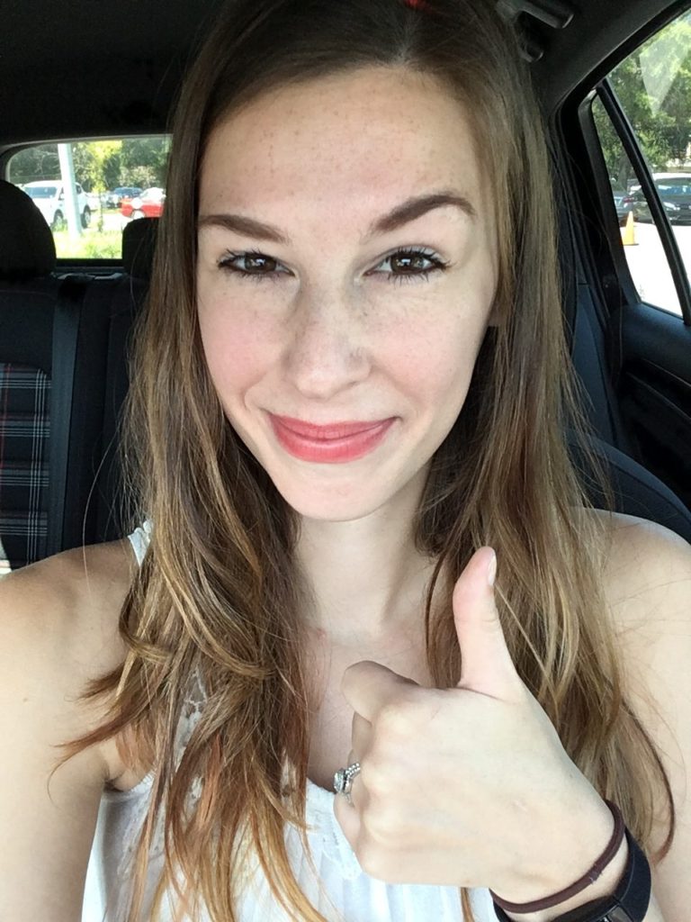 Jenna wearing white shirt in car and giving thumbs up after dxa bone density scan