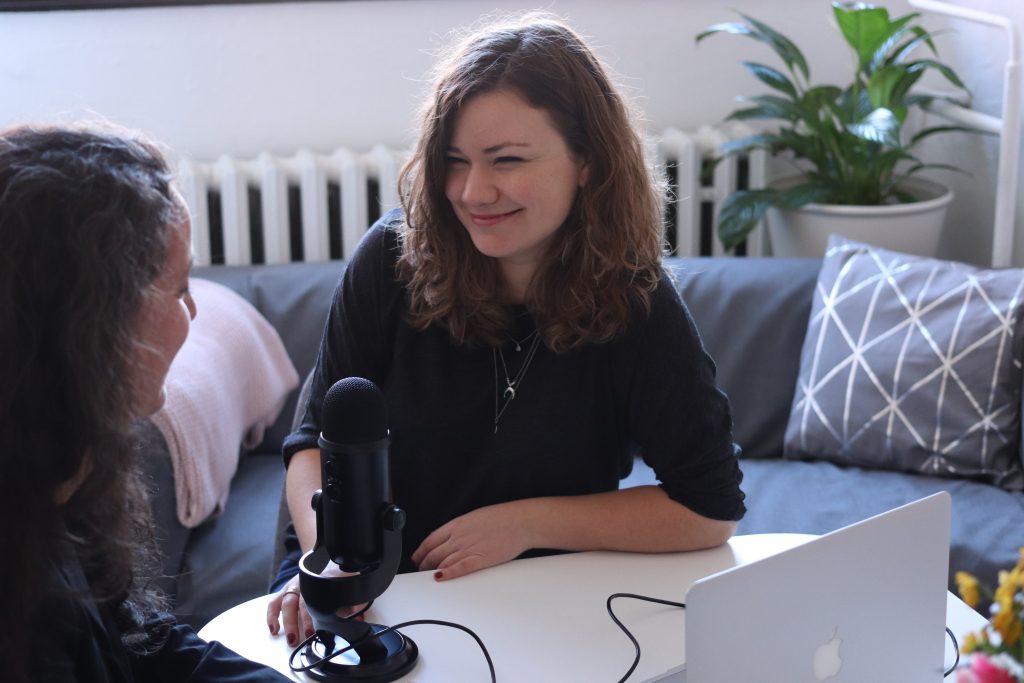 Two women recording a health podcast around a mic