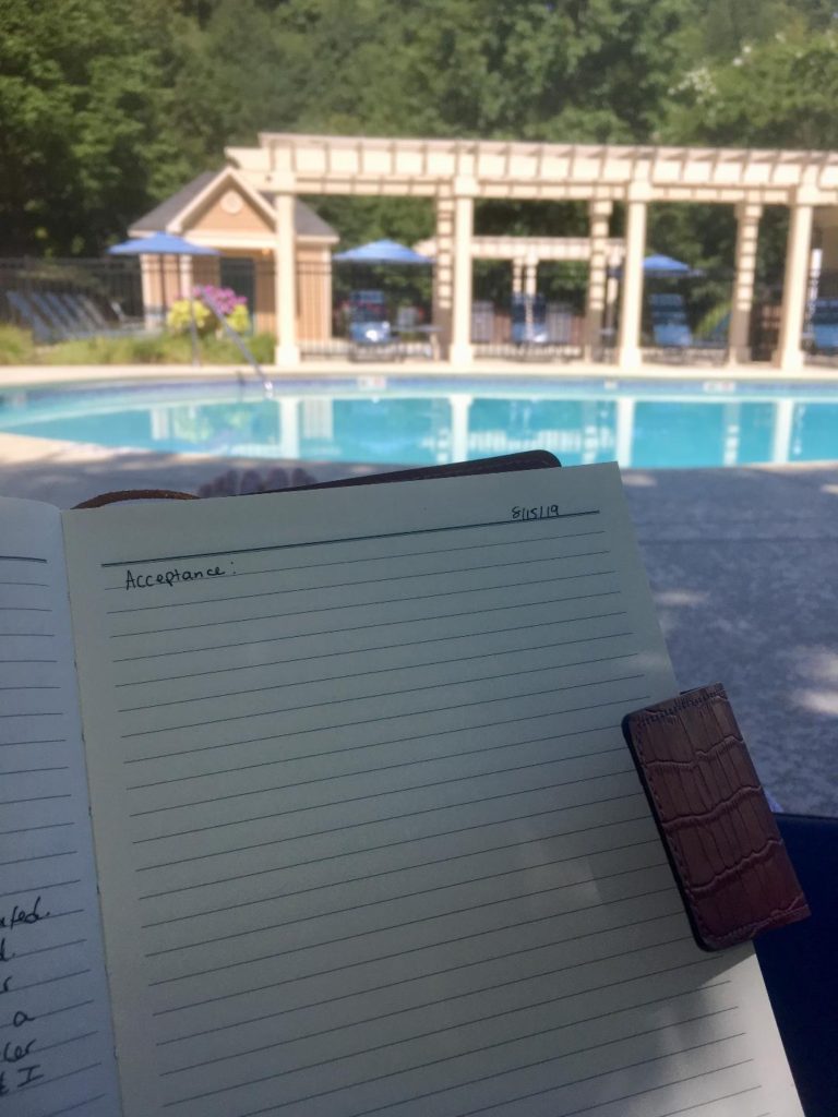 Jenna holding journal at pool with the word "Acceptance" written on the top line