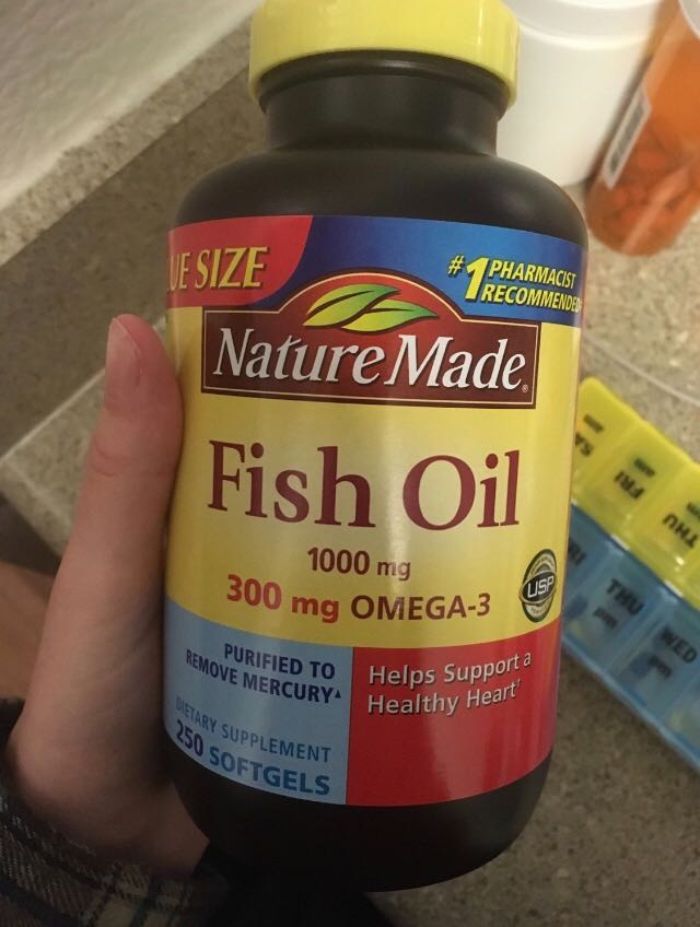 Me holding a bottle of fish oil capsules