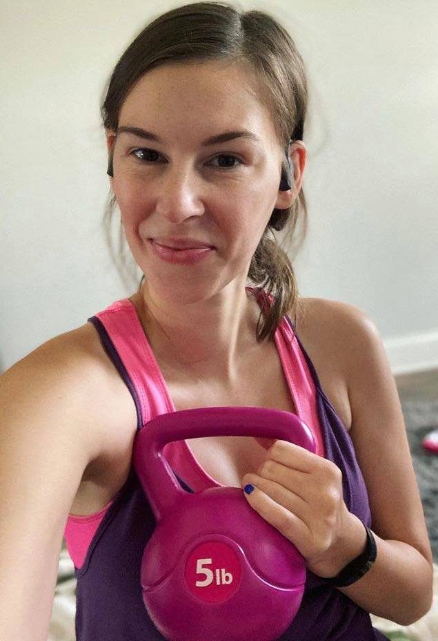 Jenna in purple workout shirt holding pink kettlebell during workout